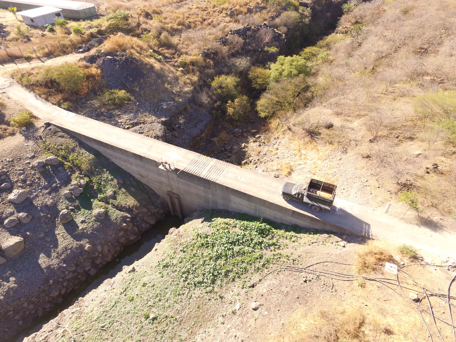 A concrete bridge and work truck crossing a narrow channel