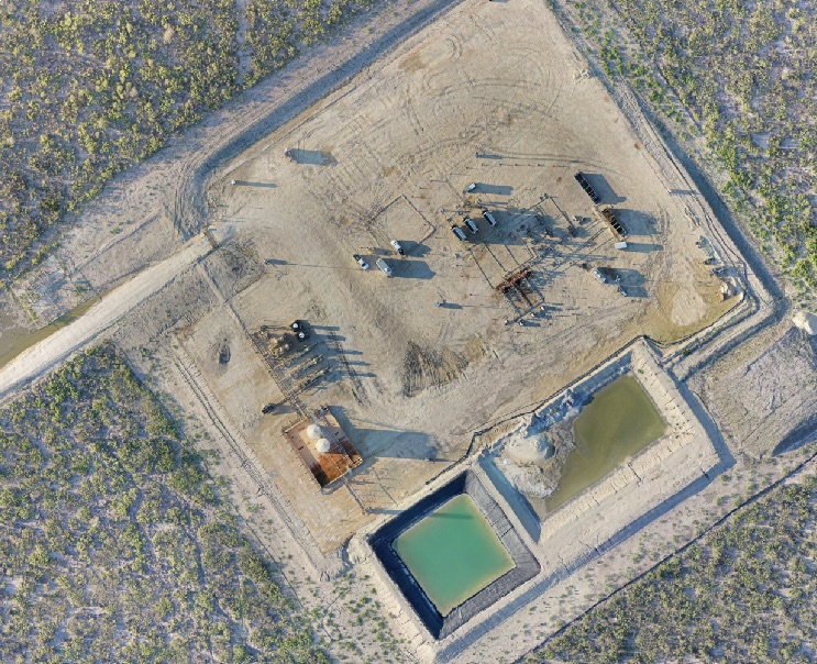 Top-down orthomosaic of an industrial yard with basins and graded material.