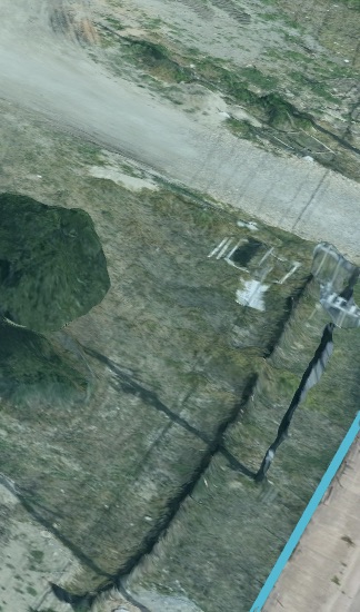 Close-up textured terrain surface showing slope and ground features near water.