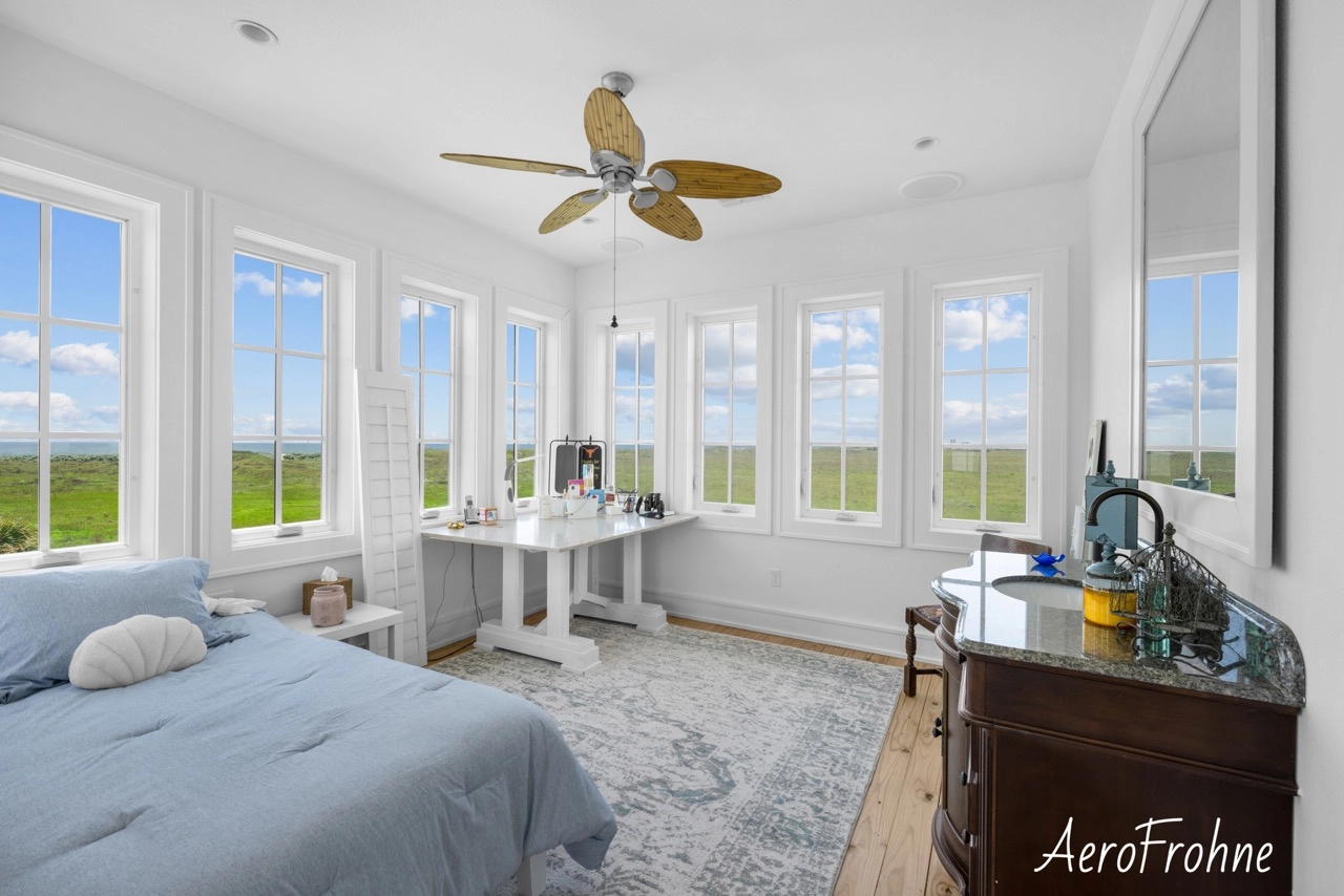 Bright bedroom with panoramic windows, ceiling fan, and workspace