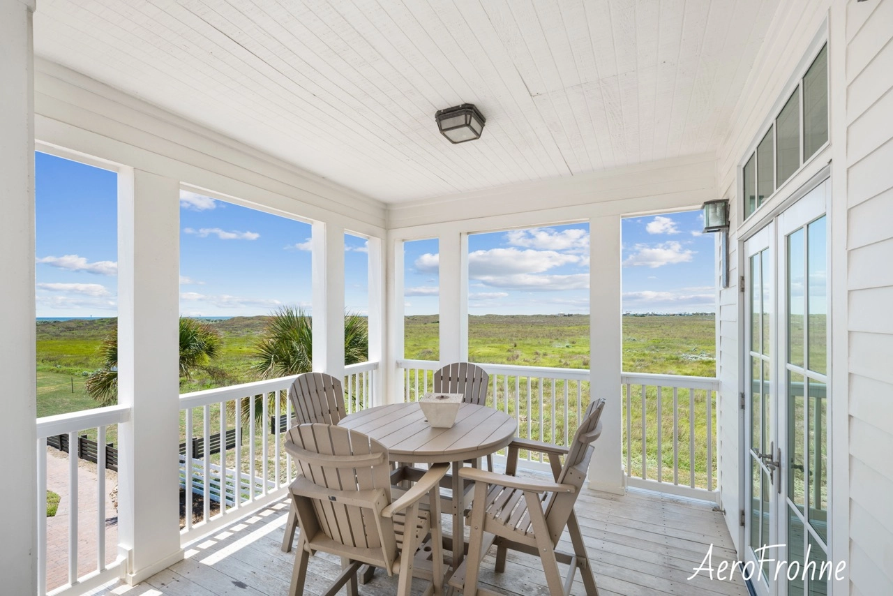 Covered balcony with outdoor dining set and coastal views