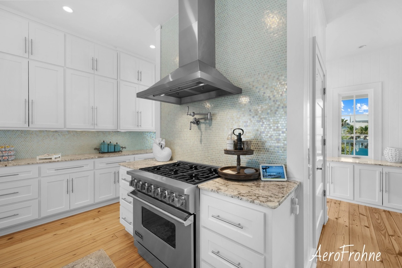 Kitchen with gas range, vent hood, and mosaic backsplash
