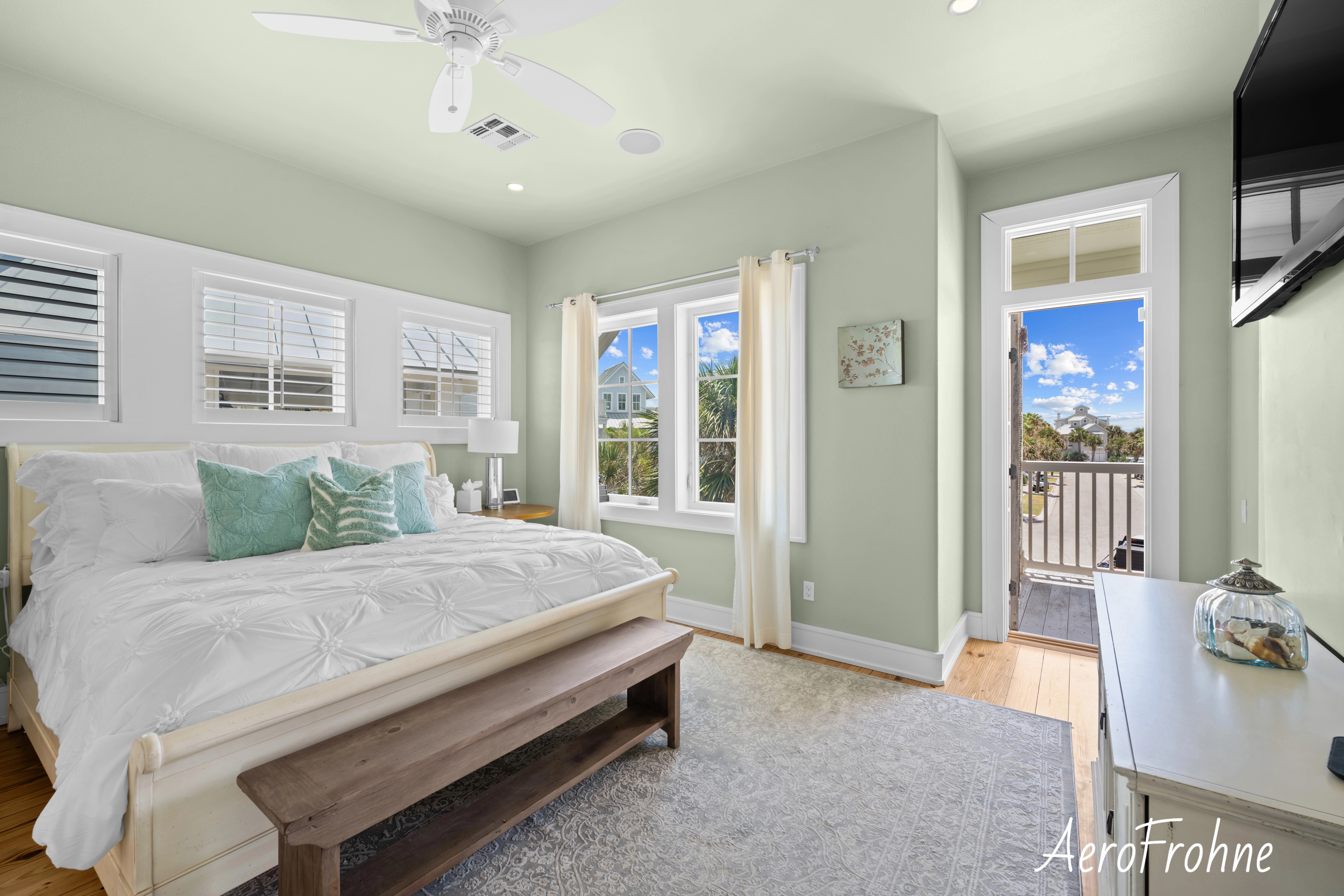 Bedroom with balcony view, white bedding, and soft green walls