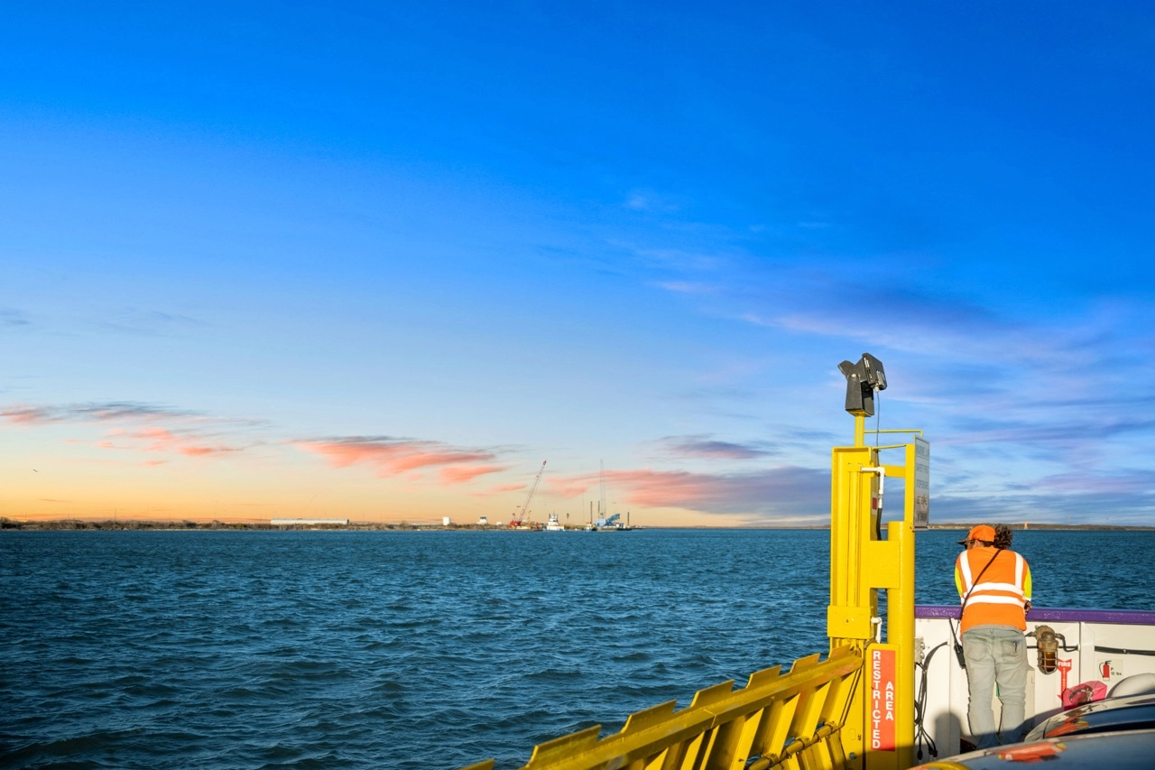 Ferry deck with worker and Gulf horizon at sunset