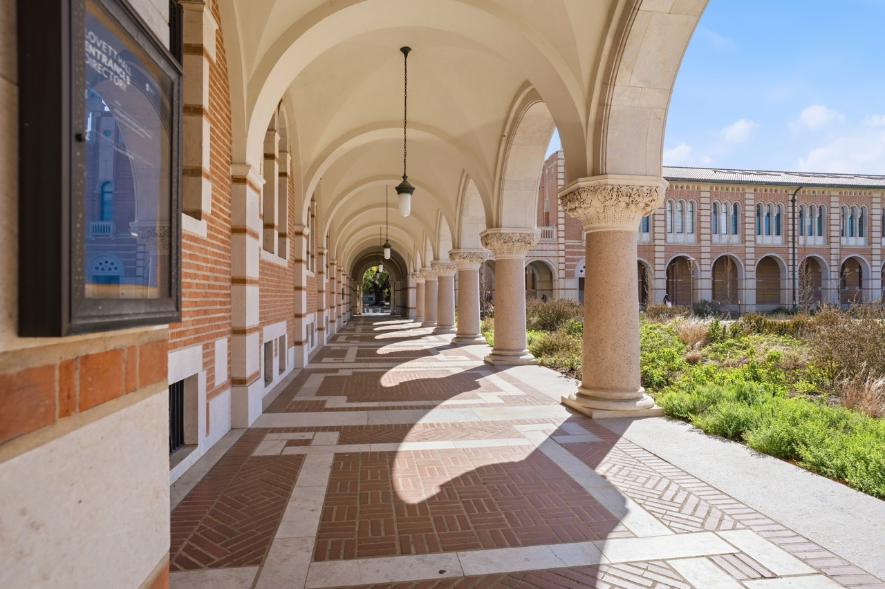 Atmospheric view through the brick arcades of Lovett Hall at Rice University, showing columns, arches, and sunlight