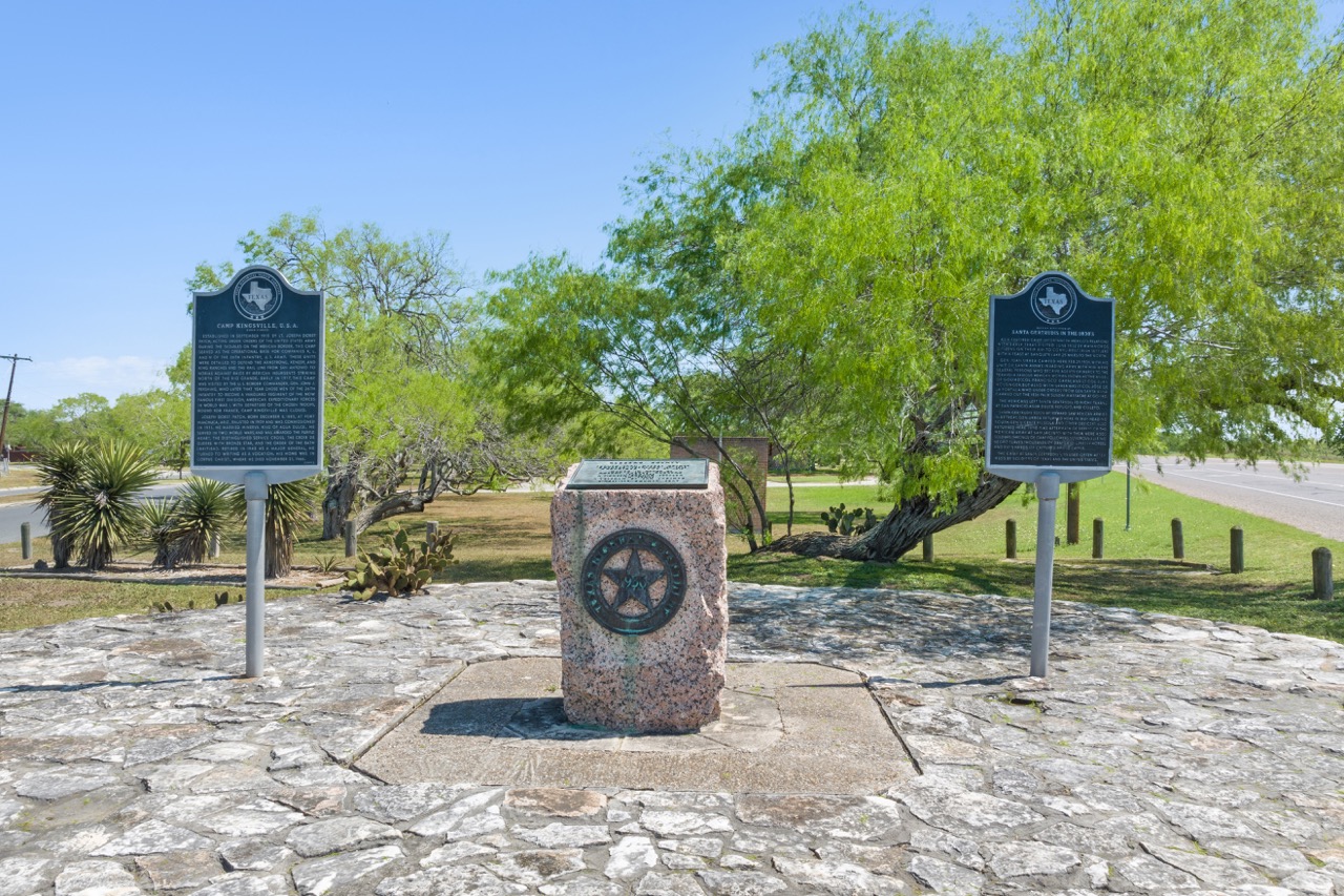 Historical marker site featuring two descriptive plaques and a central stone monument with a Texas lone star.