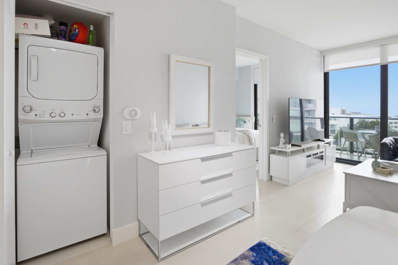 Living space with white dresser, TV, and laundry closet.