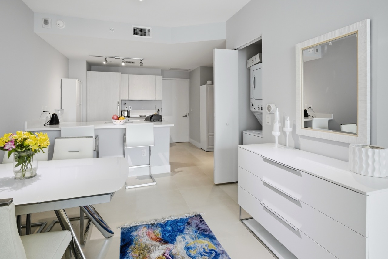 Dining area adjacent to open laundry closet with stackable units.