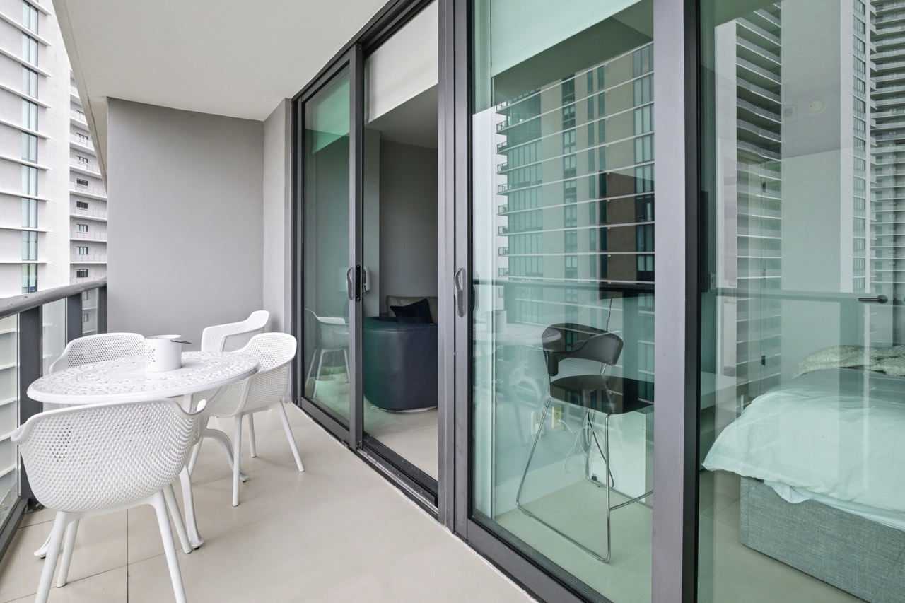 Balcony with outdoor dining set and sliding glass doors opening to a bedroom.