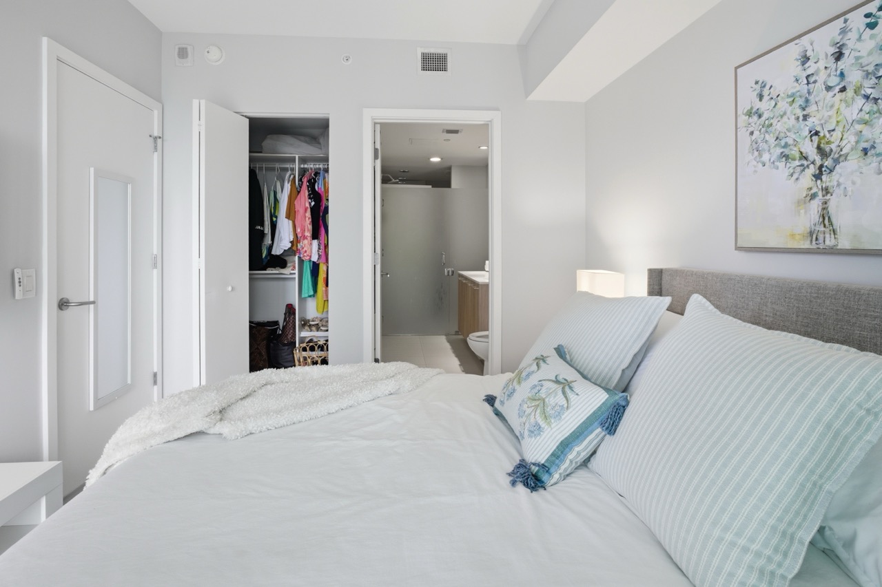 Master bedroom with grey bedframe looking towards the ensuite bathroom entrance.