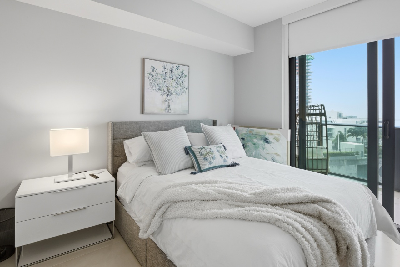 Close-up of bedroom decor featuring floral artwork, modern lamp, and white nightstand.
