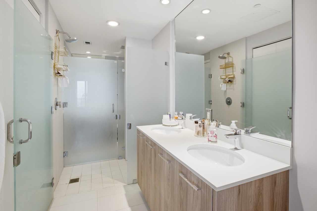 Spacious bathroom with frosted glass shower doors and contemporary fixtures.