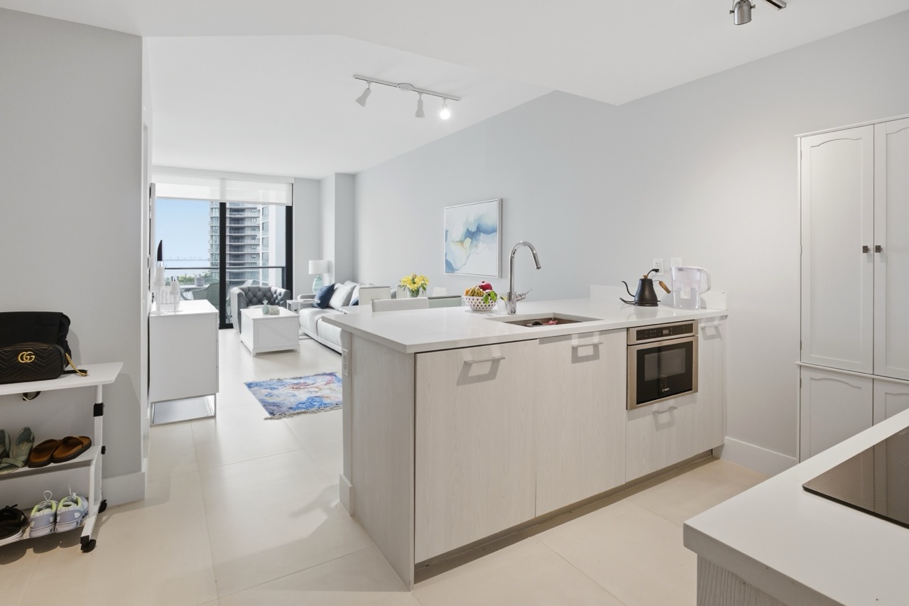 Bright open-concept living room and white kitchen with island.