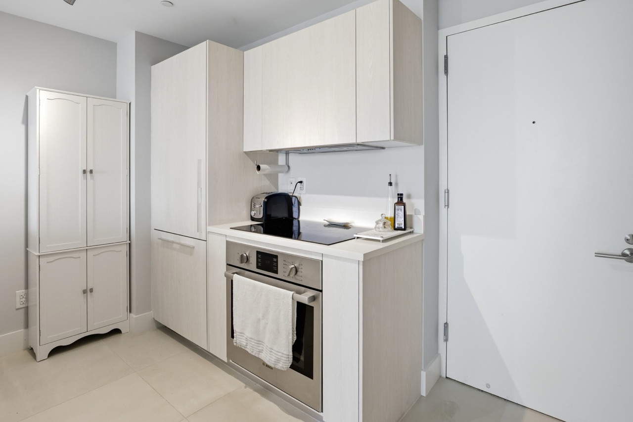 Compact modern kitchen with white cabinets and stainless appliances.