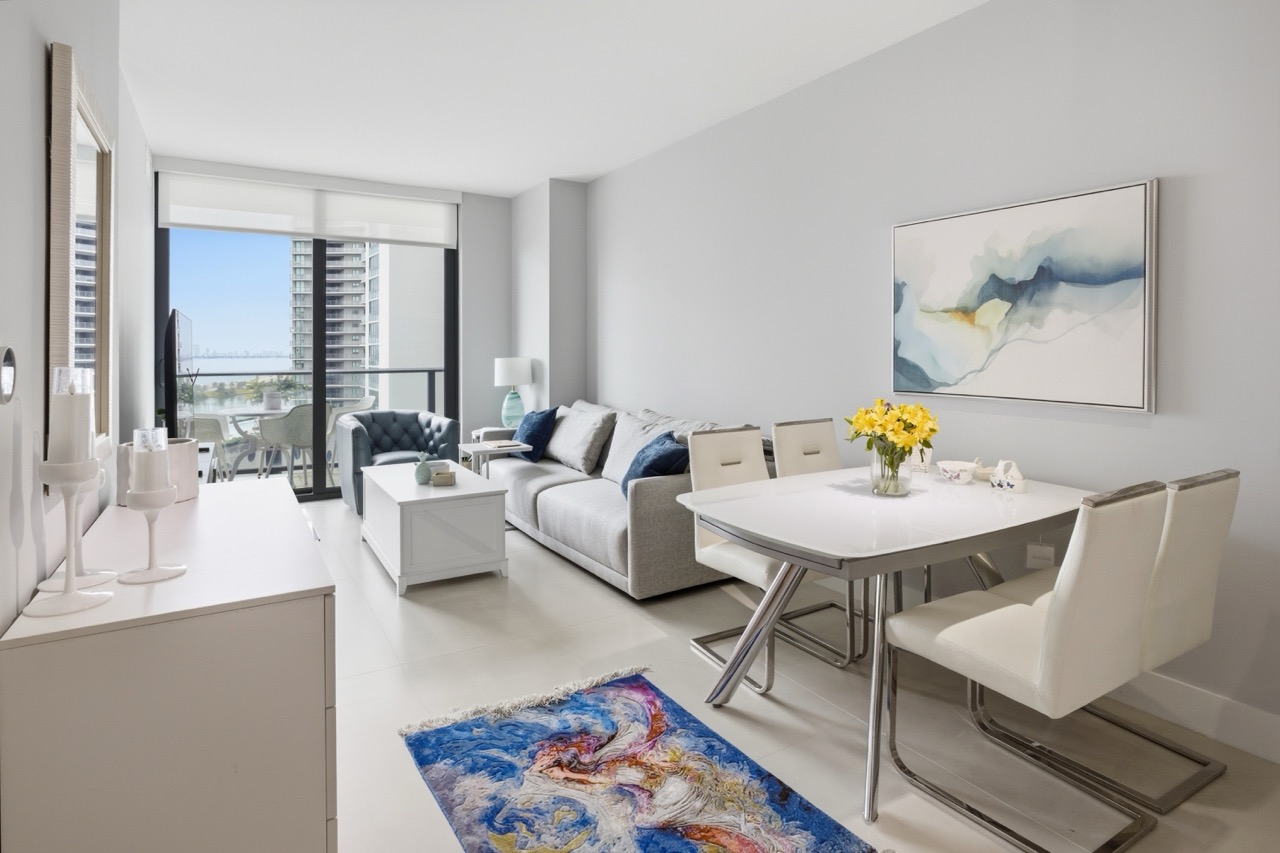 Living and dining area with grey sofa and balcony access.