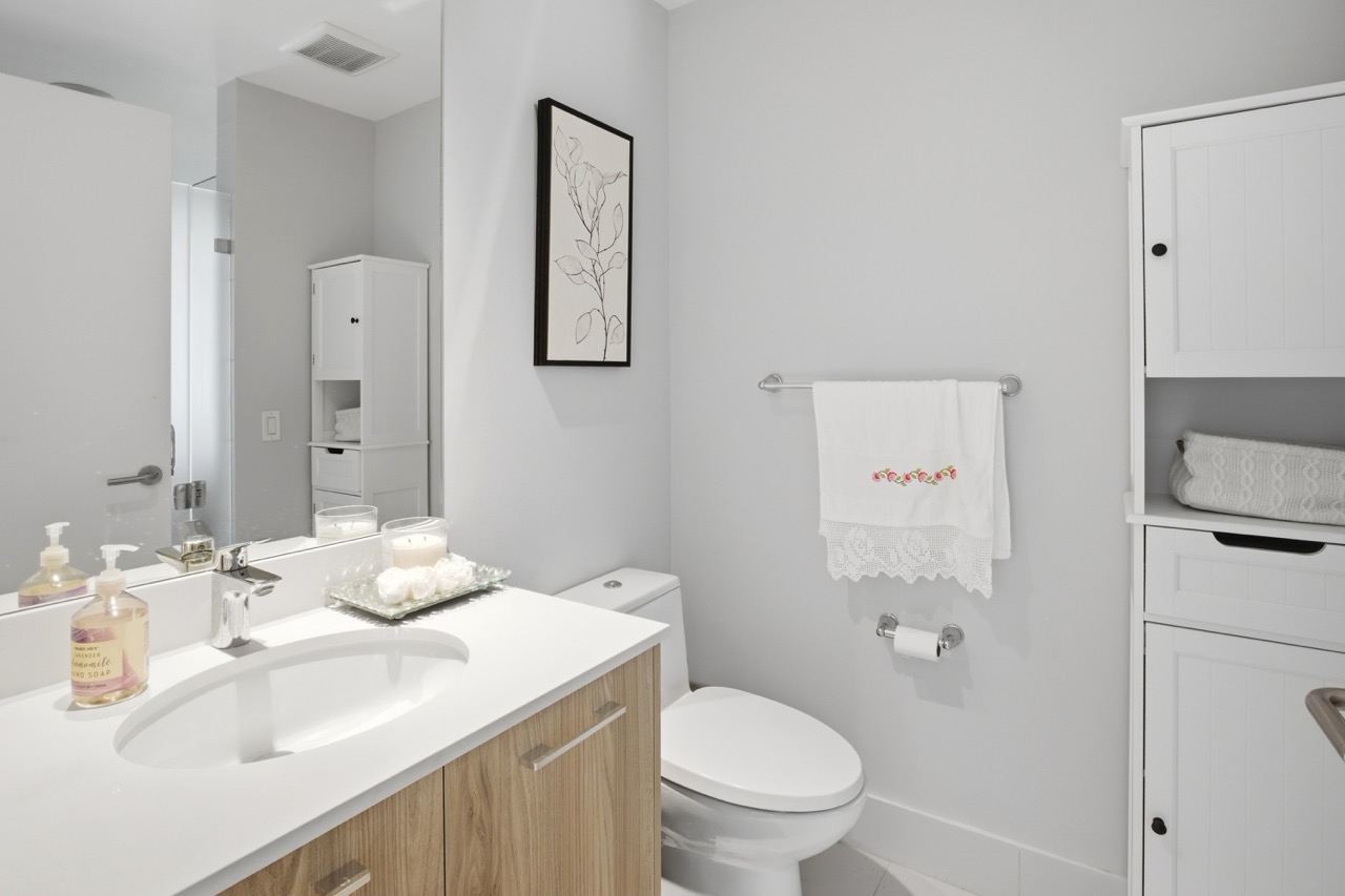 Bathroom with light wood vanity and white storage cabinet.