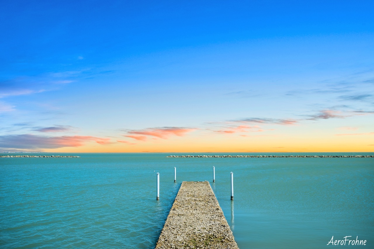 A long rock pier extending into the ocean at twilight