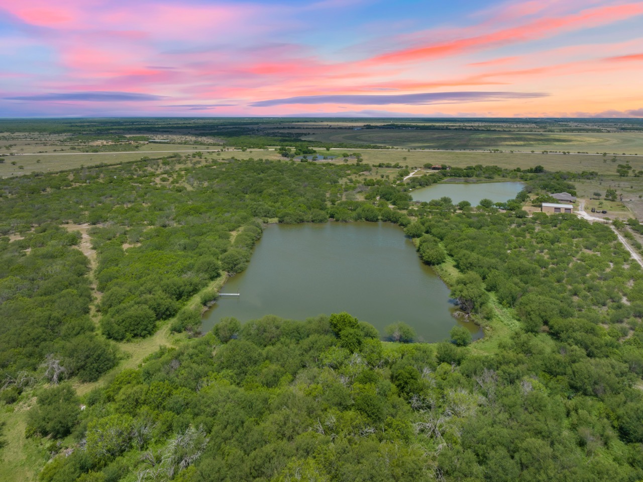 Aerial view of a pond surrounded by brush on ranch land in Alice Texas