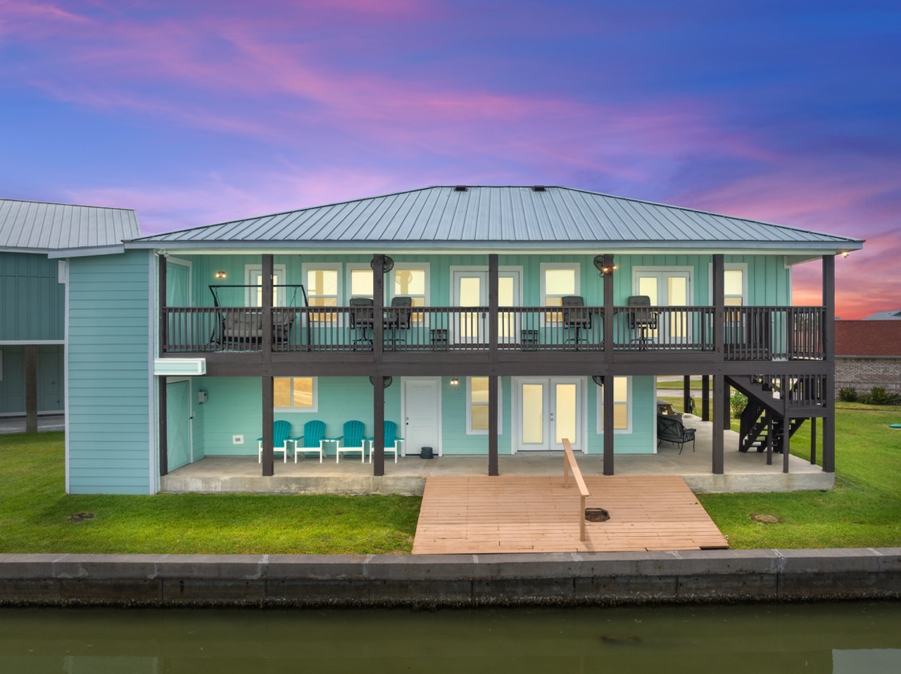 Rear view of a light blue house on stilts showing a large deck in Rockport Texas