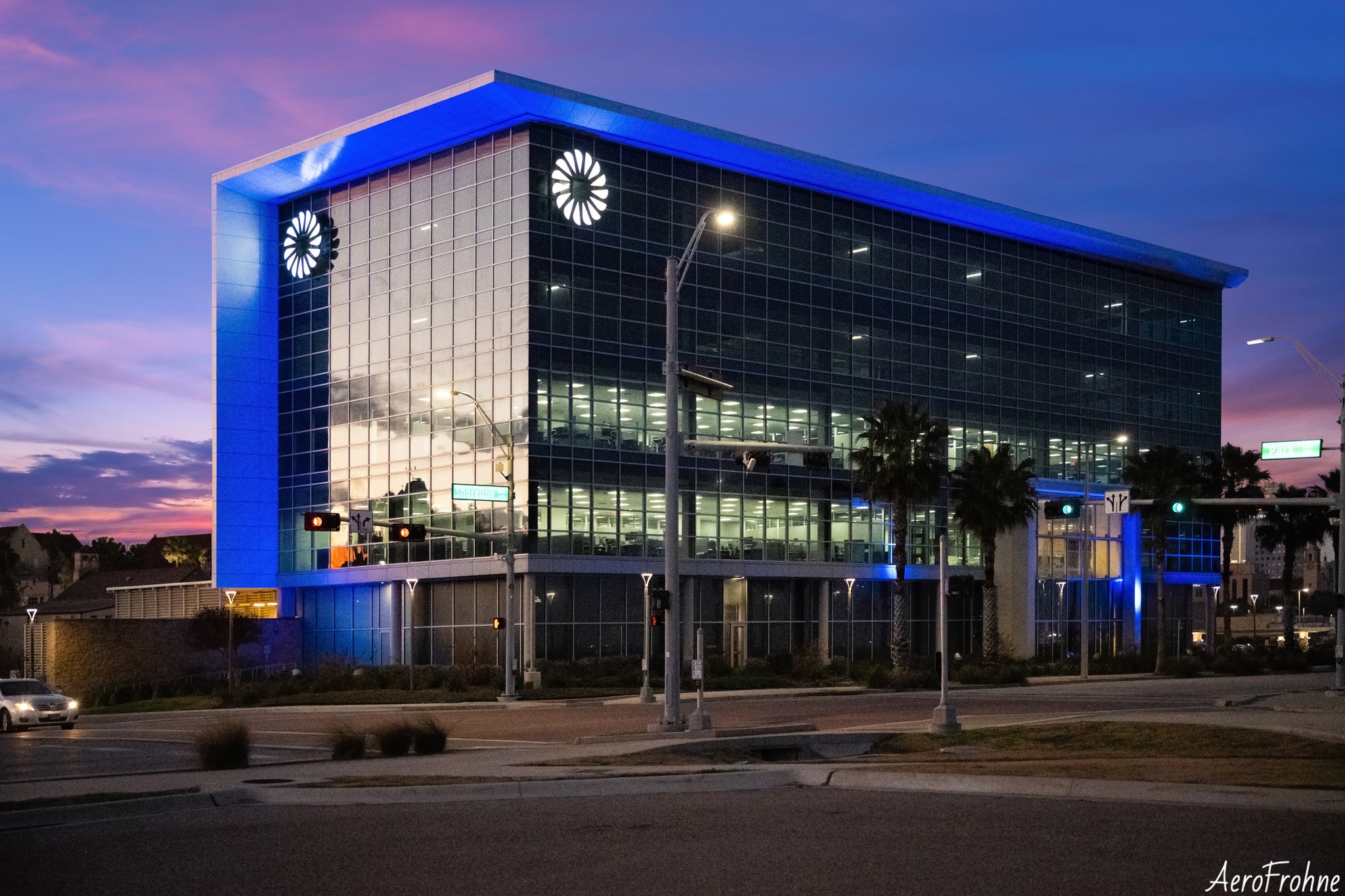 A modern glass building illuminated with blue light at twilight in Corpus Christi Texas