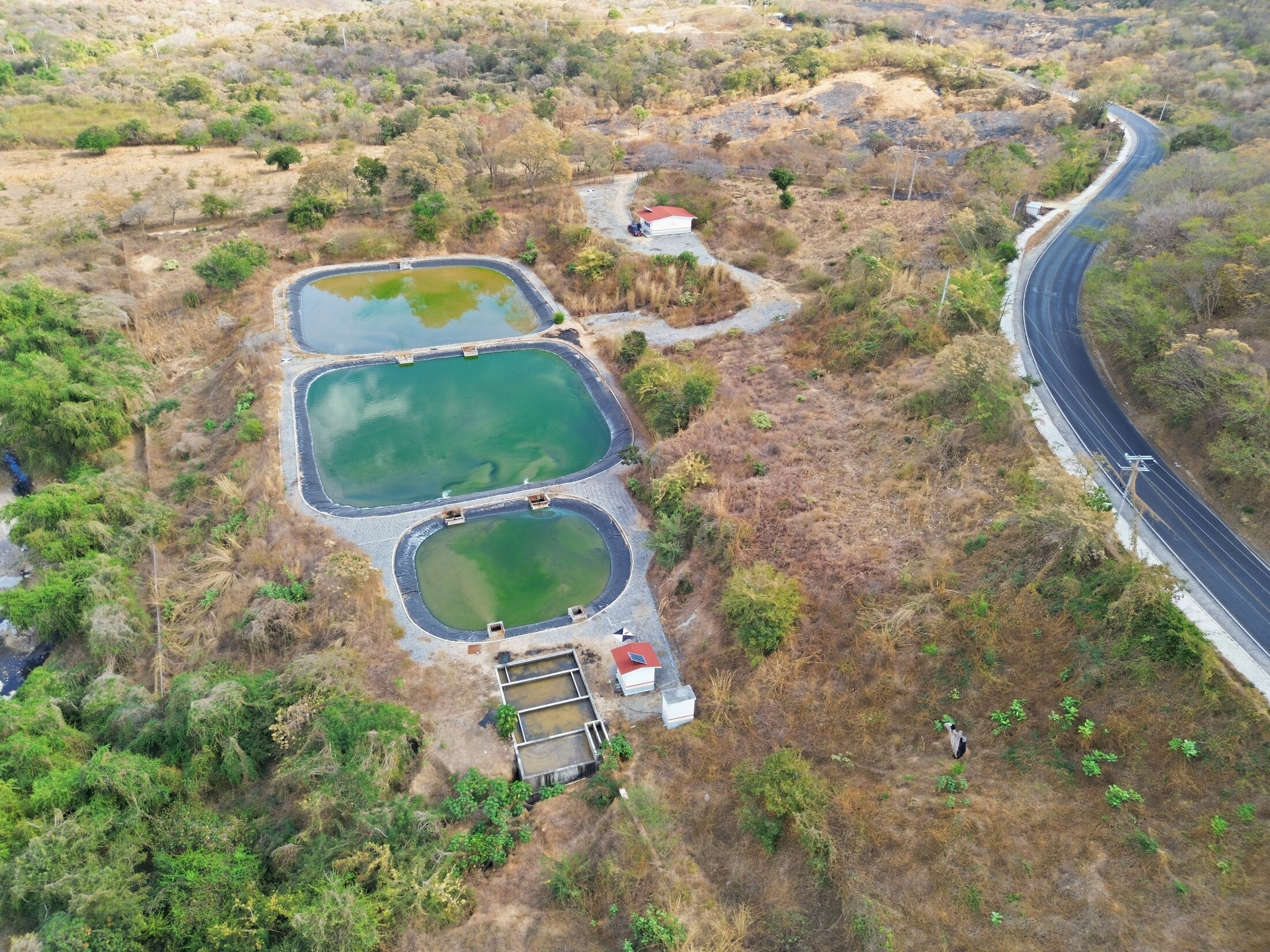 Aerial survey of treatment ponds beside a paved road corridor