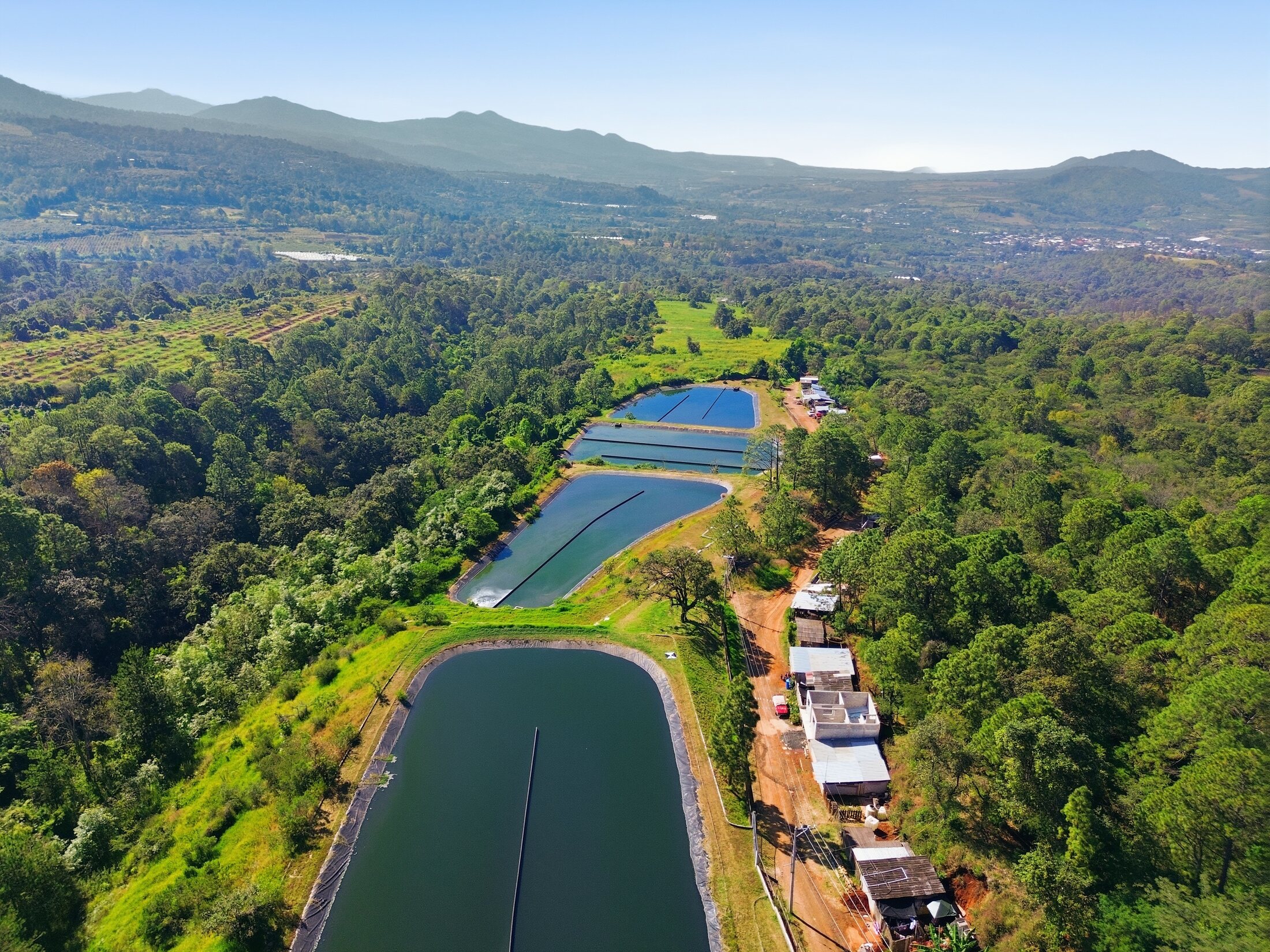 Aerial topographic view of aquaculture ponds surrounded by mountain terrain